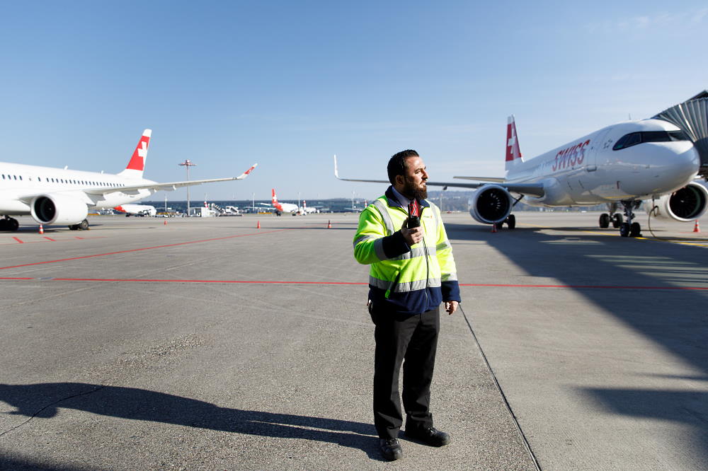 Un agent de piste d'aéroport aide les avions à se garer après leur atterissage.