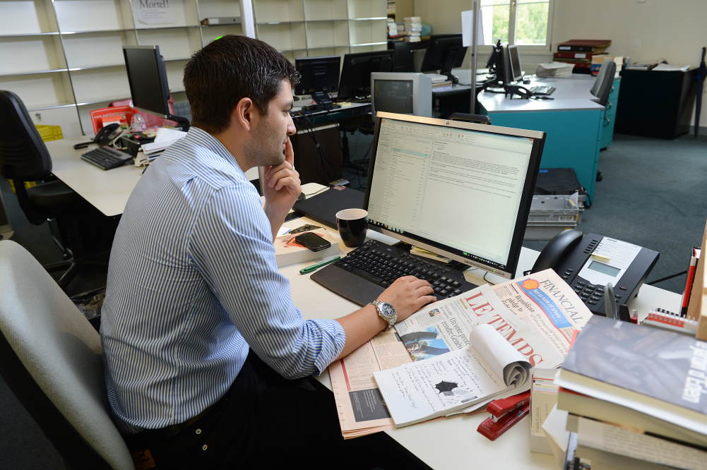 Un journaliste rédige un article à son bureau