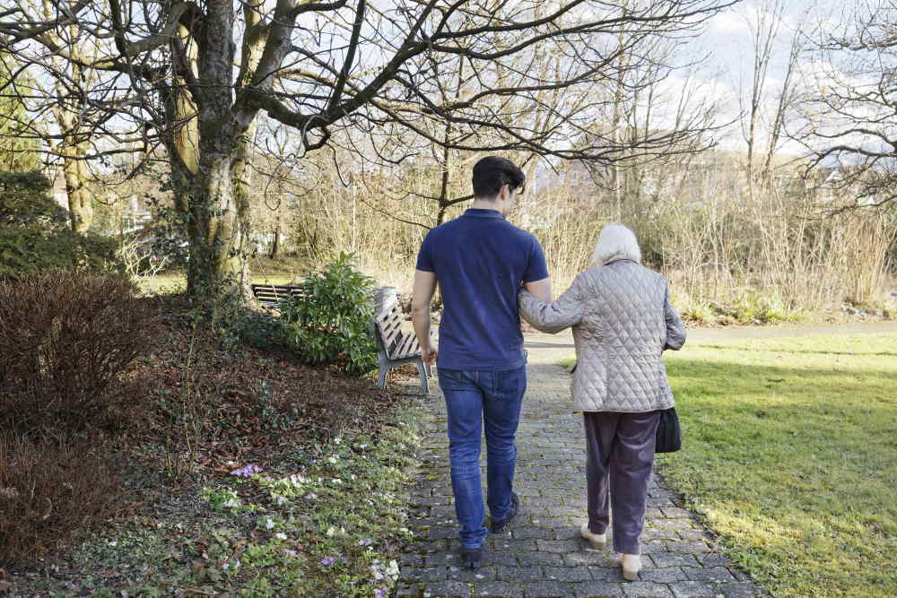 Un homme accompagne une dame âgée en promenade.