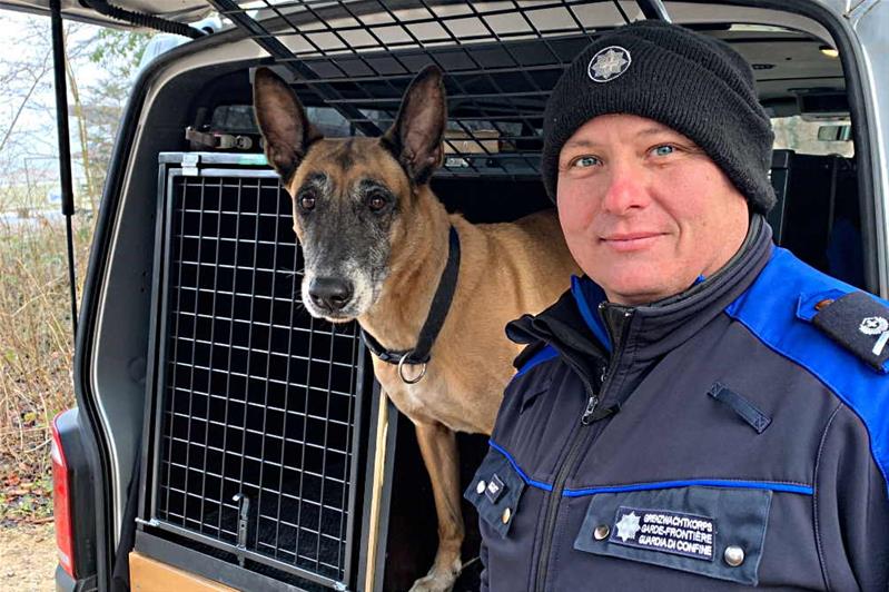 Un homme en uniforme de l'Office fédéral de la douane et des frontières se tient près de Dynamo, chien de service de la douane