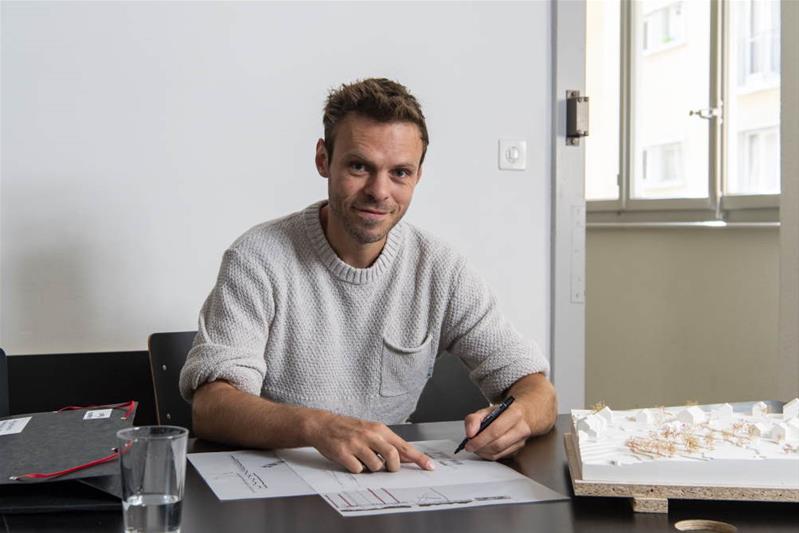 Un homme est assis à son bureau et dessine des plans