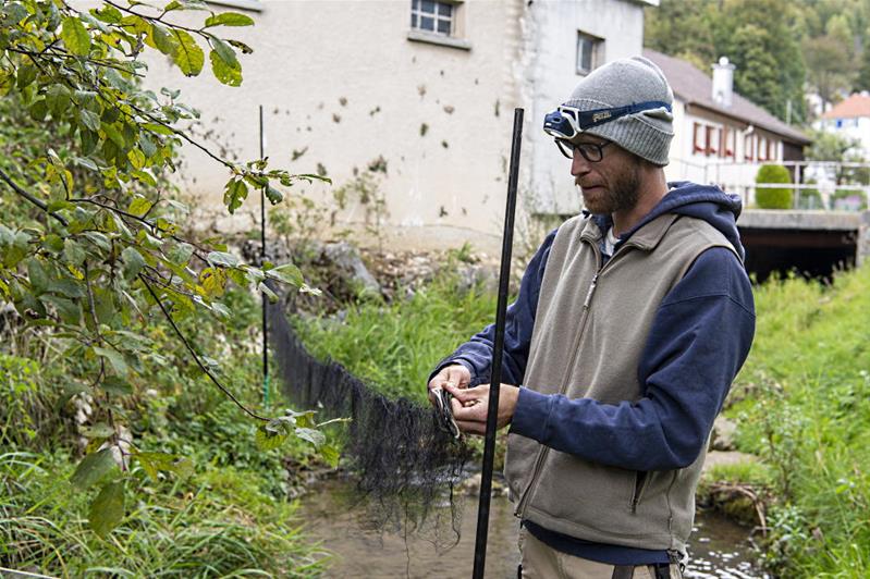 Un homme prépare un filet près d'une rivière.