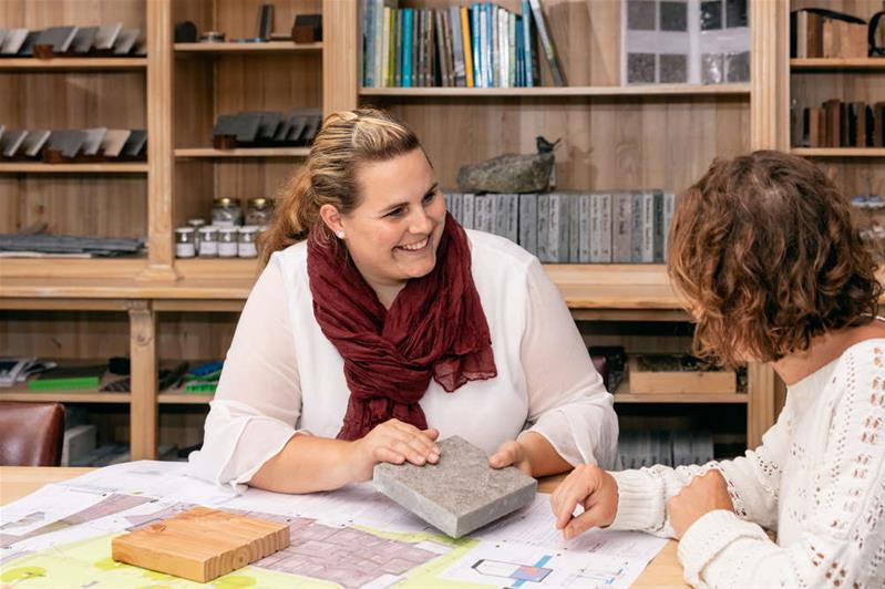 Une femme conseille une cliente dans le choix de matériaux pour un aménagement extérieur