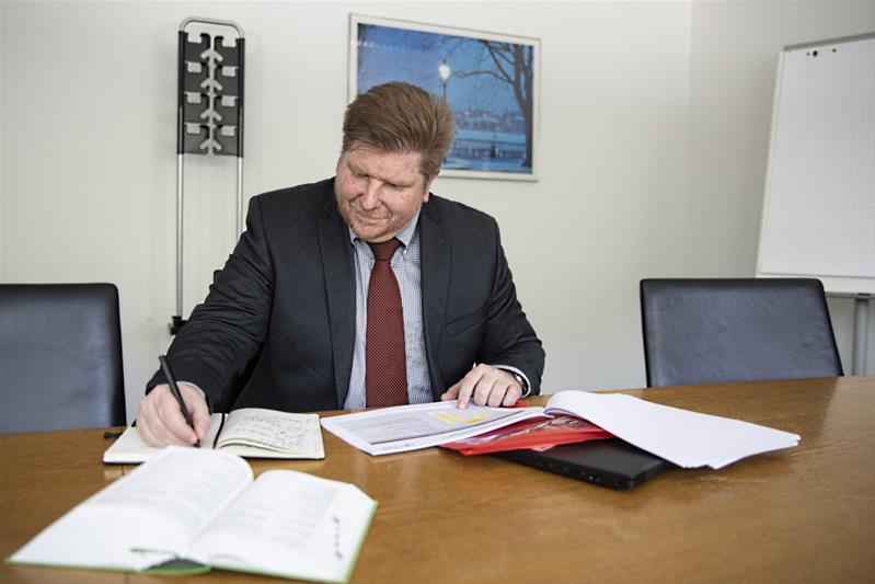 Un homme écrit un document à sa table de travail.