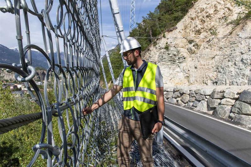 Un homme contrôle une passerelle en montagne