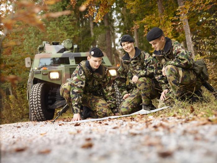 Trois membres de l'armée suisse étudient une carte.