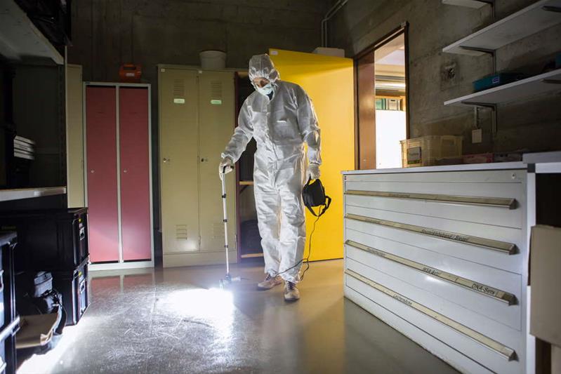 Un homme en combinaison blanche inspecte une pièce.