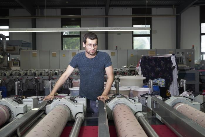 Un homme surveille l'impression sur la machine rotative.