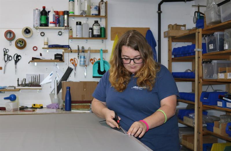 Stephanie Salvini découpe du cuir sur une table.