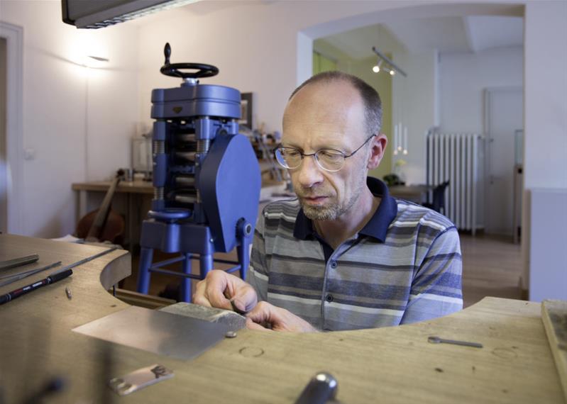 Un homme fabrique un bijou dans son atelier.