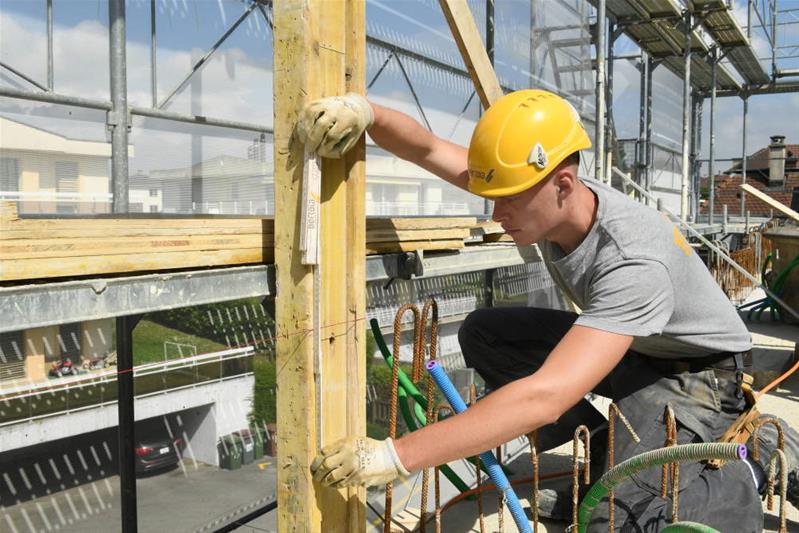 Un apprenti maçon AFP vérifie la hauteur d'un mur qui sera construit avec des briques.