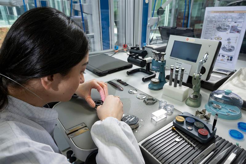 Une apprentie monte les composants du mouvement d'une montre.