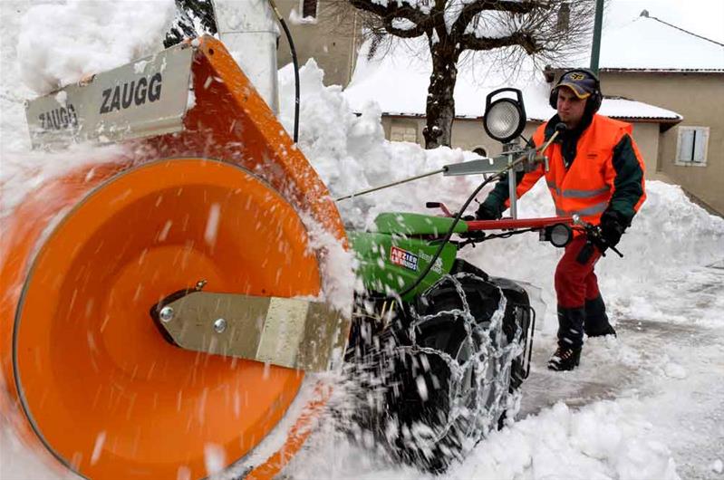 Un apprenti déblaie la neige à l’aide d’une fraiseuse.
