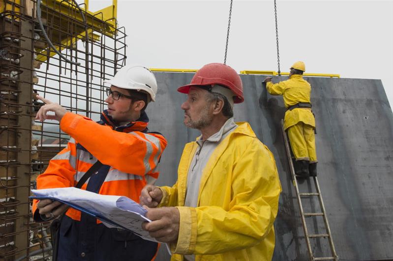 Deux hommes sur un chantier discutent du travail à effectuer.