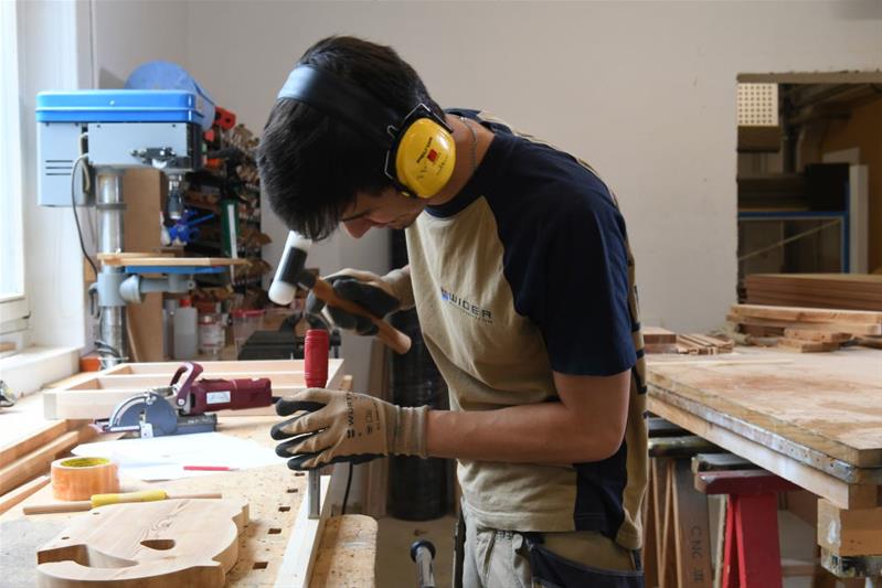 Un homme travaille sur une pièce en bois.