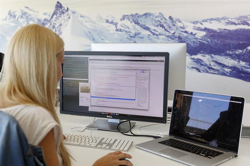 Une jeune femme travaille avec deux écrans dans un bureau.