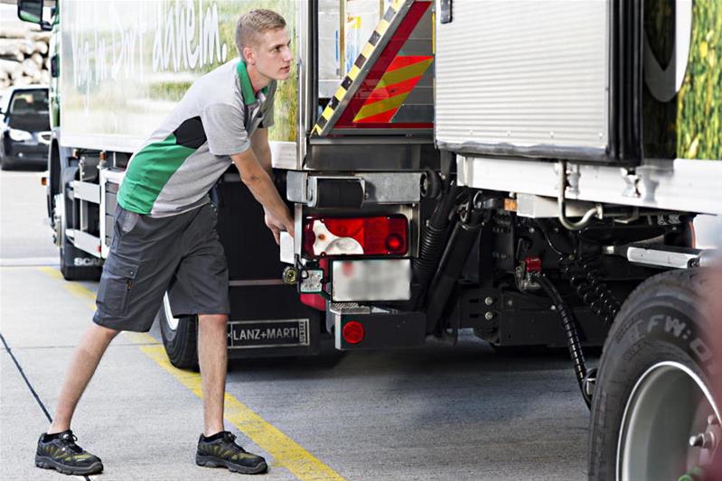 Le conducteur d'un poids lourd vérifie les fixations de la remorque.