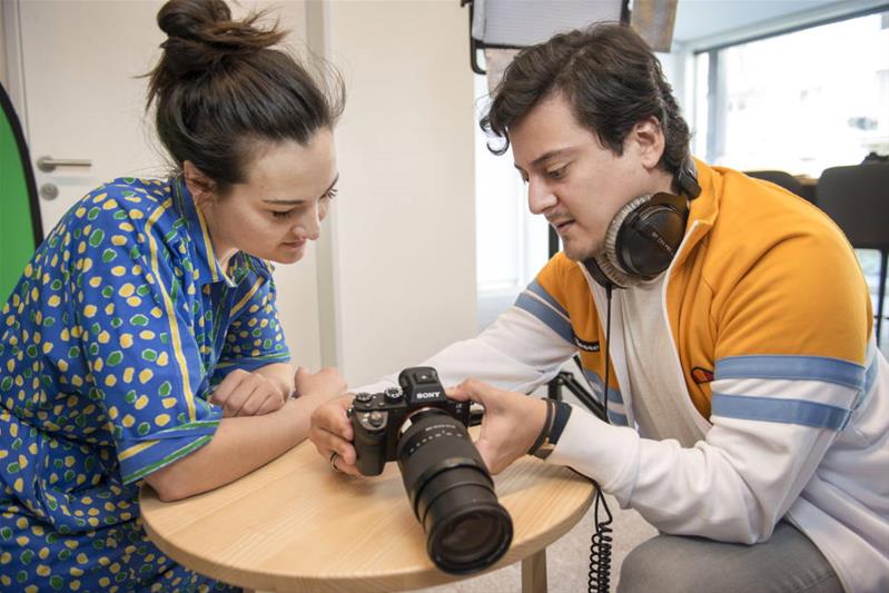 Un photographe montre une photo à une cliente sur l'écran de son appareil.