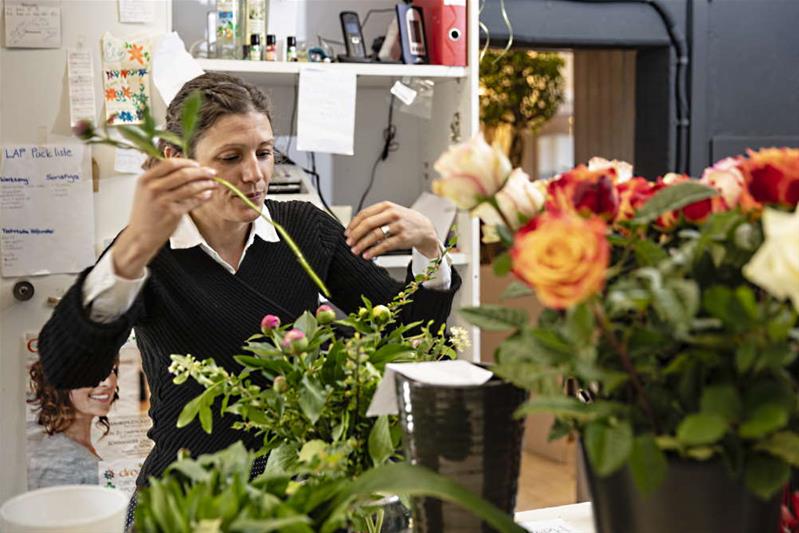Une femme arrange un bouquet dans une boutique de fleurs.
