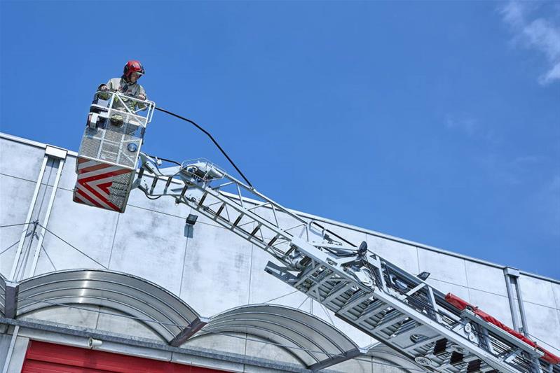 Un sapeur-pompier se trouve en hauteur, sur un bras élévateur articulé.