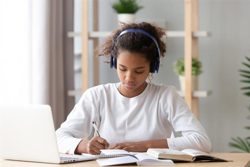 Une jeune fille rédige une lettre devant son ordinateur.