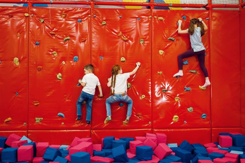 Des enfants escaladent un mur de grimpe en salle