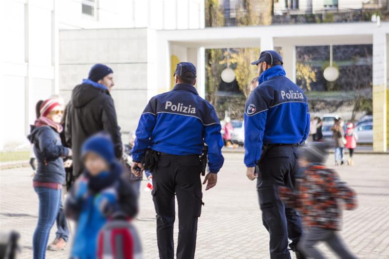 Deux policiers parlent à des parents dans la cour d'une école.