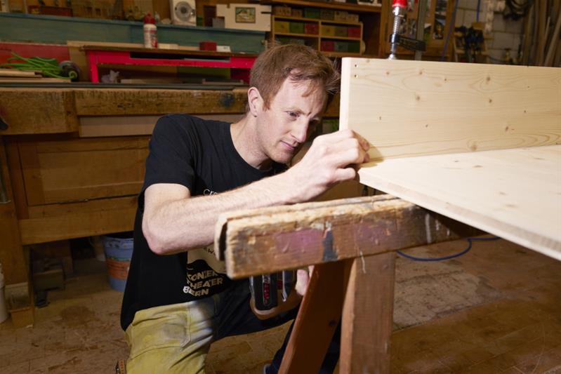 Dominik Lehmann Flury est en train de construire un caisson en bois.