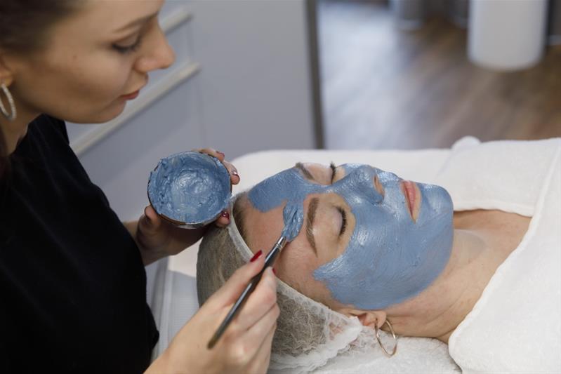 Debora Widmer applique un masque sur le visage d'une cliente.