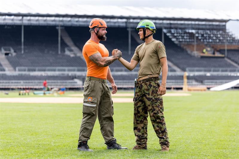 Une personne de l'armée et une personne de la protection civile se serrent la main.