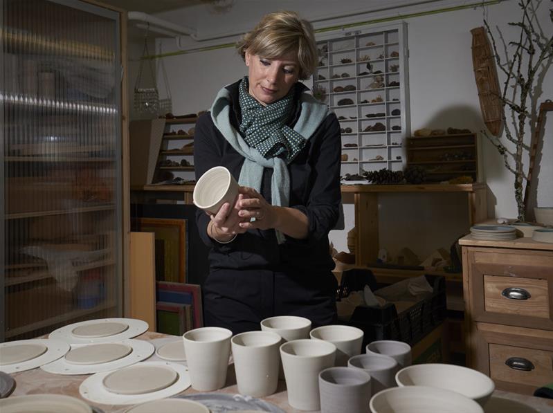 Une femme contrôle la réalisation de produits en céramique.