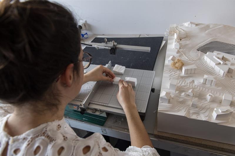 Une femme travaille les pièces d’une maquette.