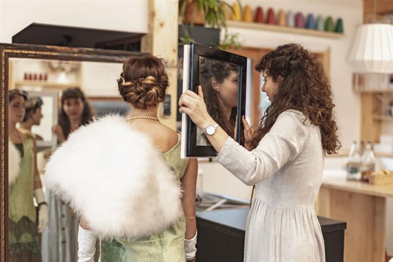 Cécile Revaz tient un miroir devant une actrice en costumes de spectacle.