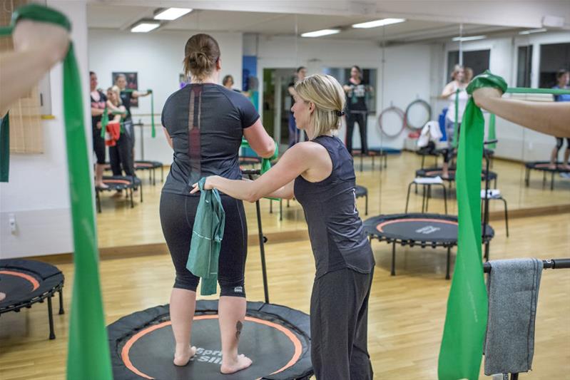 Une enseignante de fitness aide une élève à réaliser un exercice.