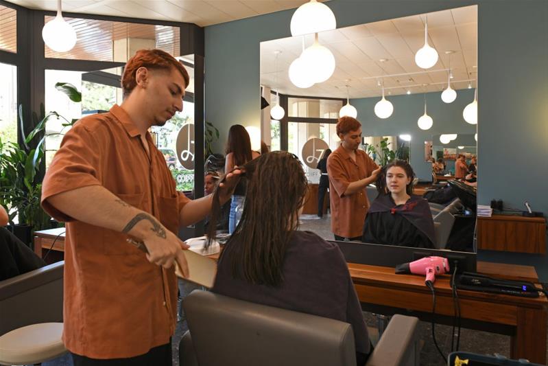 Un apprenti coupe les cheveux d'une personne dans un salon de coiffure.