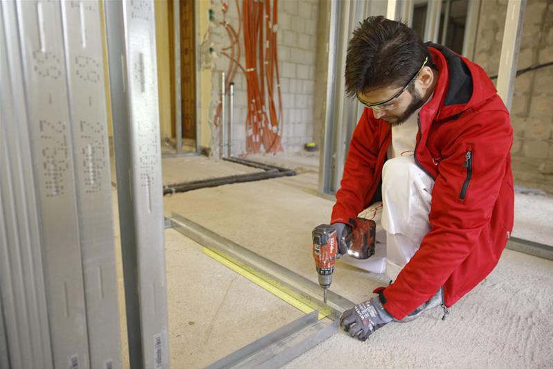 Un apprenti rend la surface d'un mur plate.