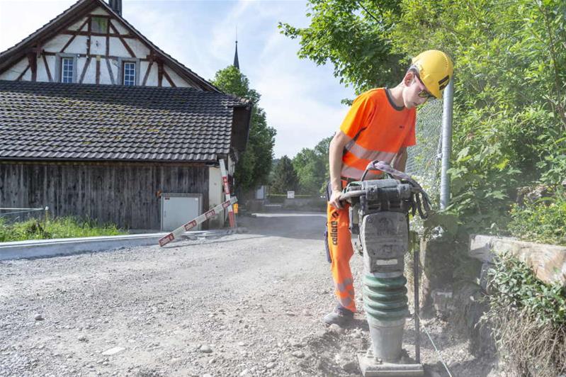 Un apprenti aplanit une route avec une machine.