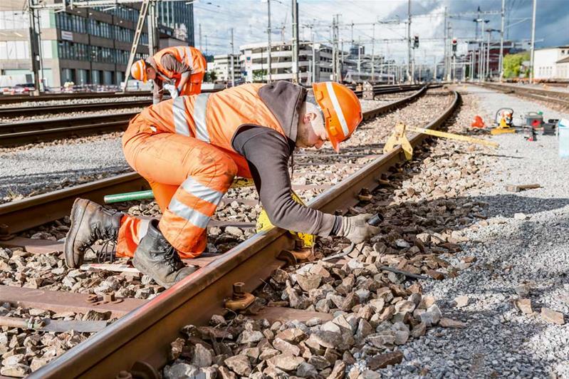 Un apprenti travaille sur des rails de chemins de fer.