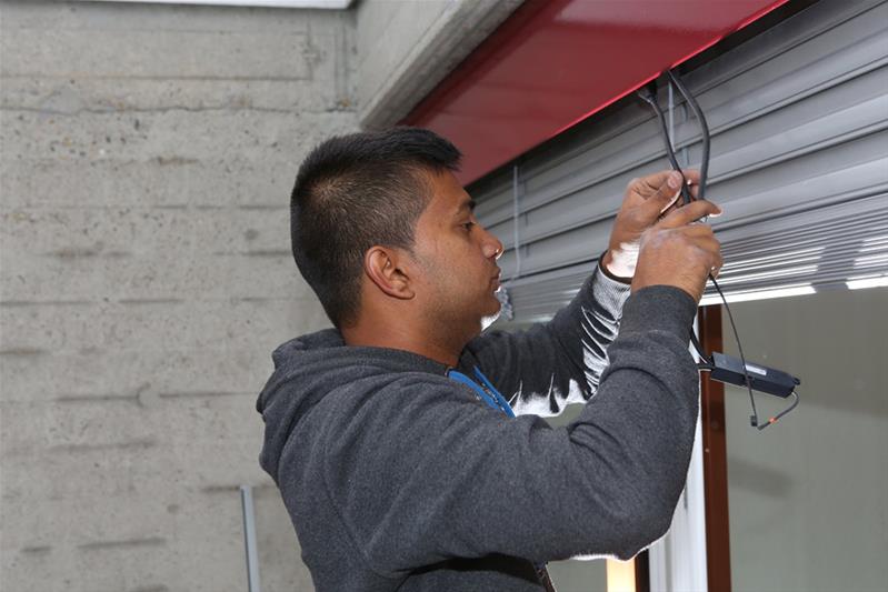 Un apprenti règle le moteur d'un store.