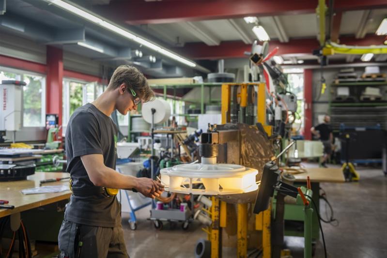 Un apprenti contrôle la qualité d'une roue en plastique.