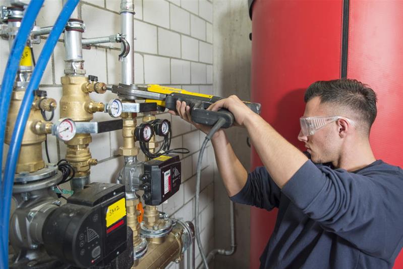 Un apprenti assemble les tuyaux d'une canalisation.