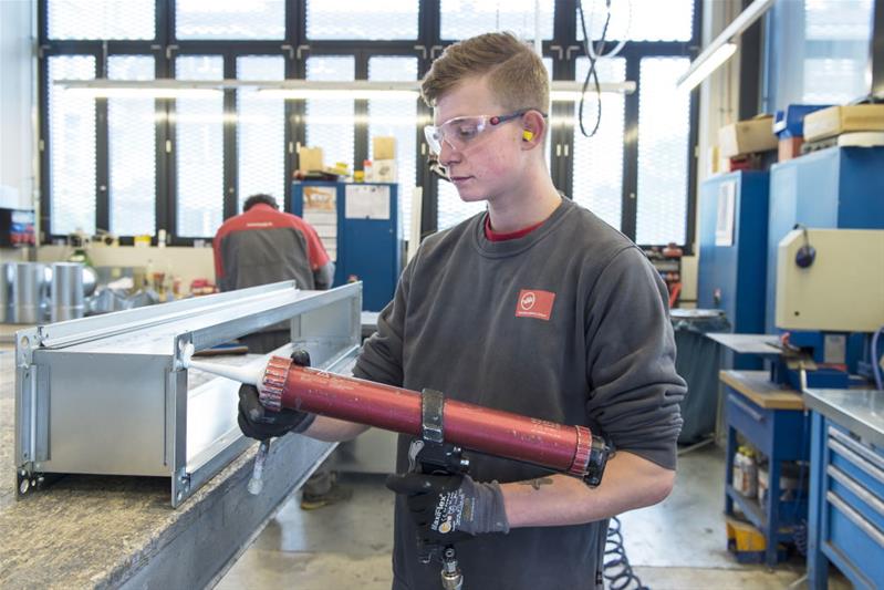 Un apprenti fabrique un conduit de ventilation.