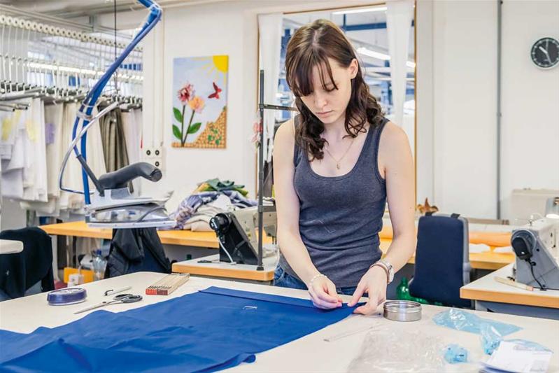 Une apprentie travaille avec une aiguille sur un morceau de tissu.