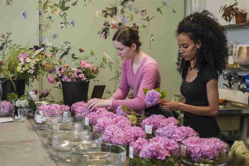 Deux fleuristes réalisent des arrangements de fleurs.